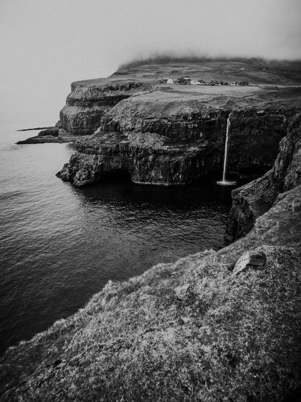 grayscale photo of rocky mountain beside sea