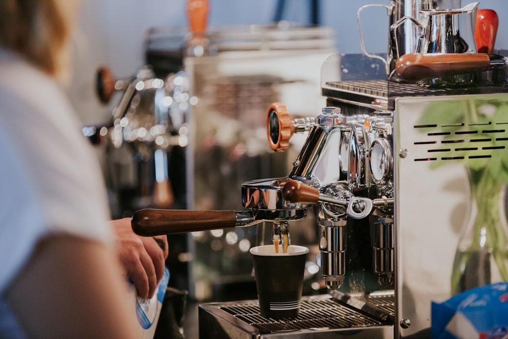 Person gießt Kaffee auf schwarzen Keramikbecher