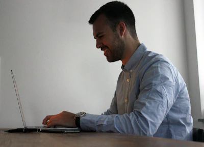 A person happily working on a laptop in a bright, homey environment.