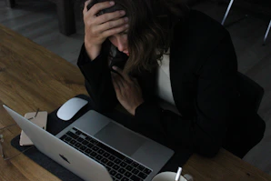 stressed woman with head in hands at laptop