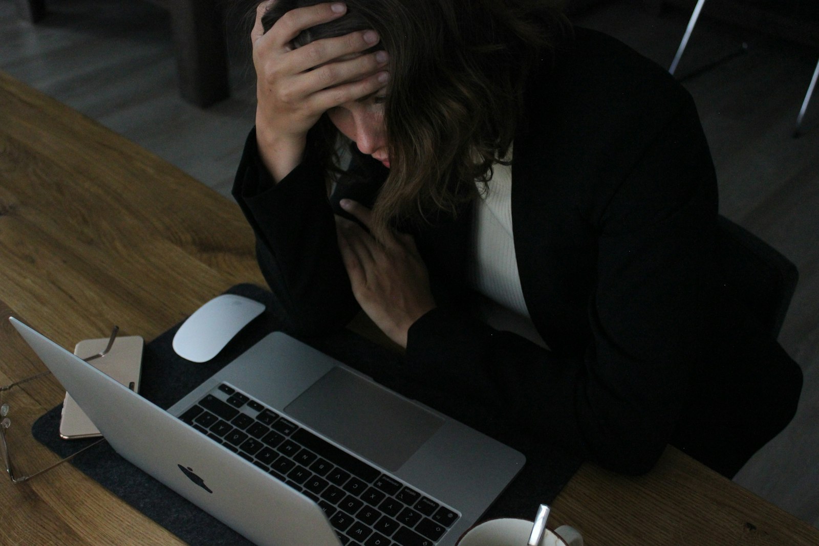A stressed person with head in hands at a laptop