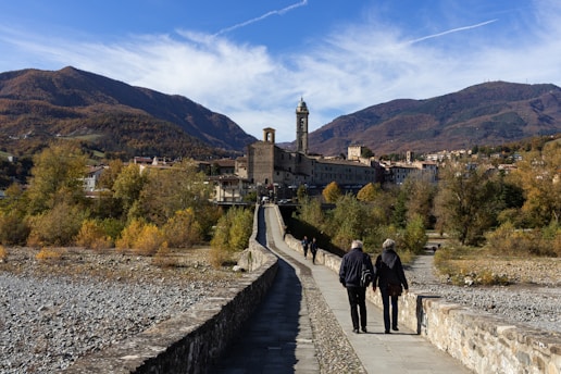 man and woman walking on pathway near brown concrete building during daytime