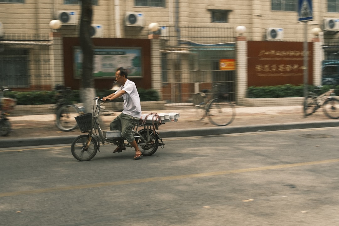 man in white dress shirt riding on black bicycle on road during daytime