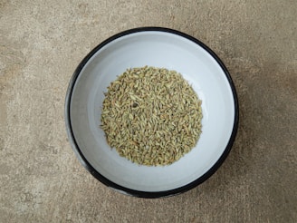 Golden fennel seeds displayed in a traditional Indian bowl.