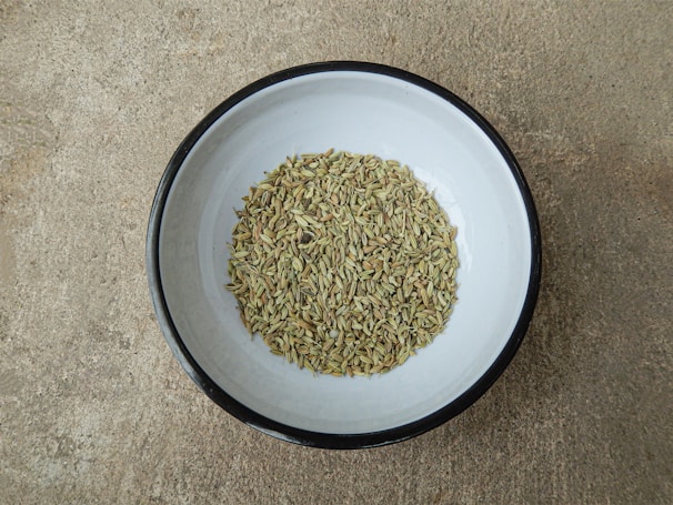 Golden fennel seeds displayed in a traditional Indian bowl.
