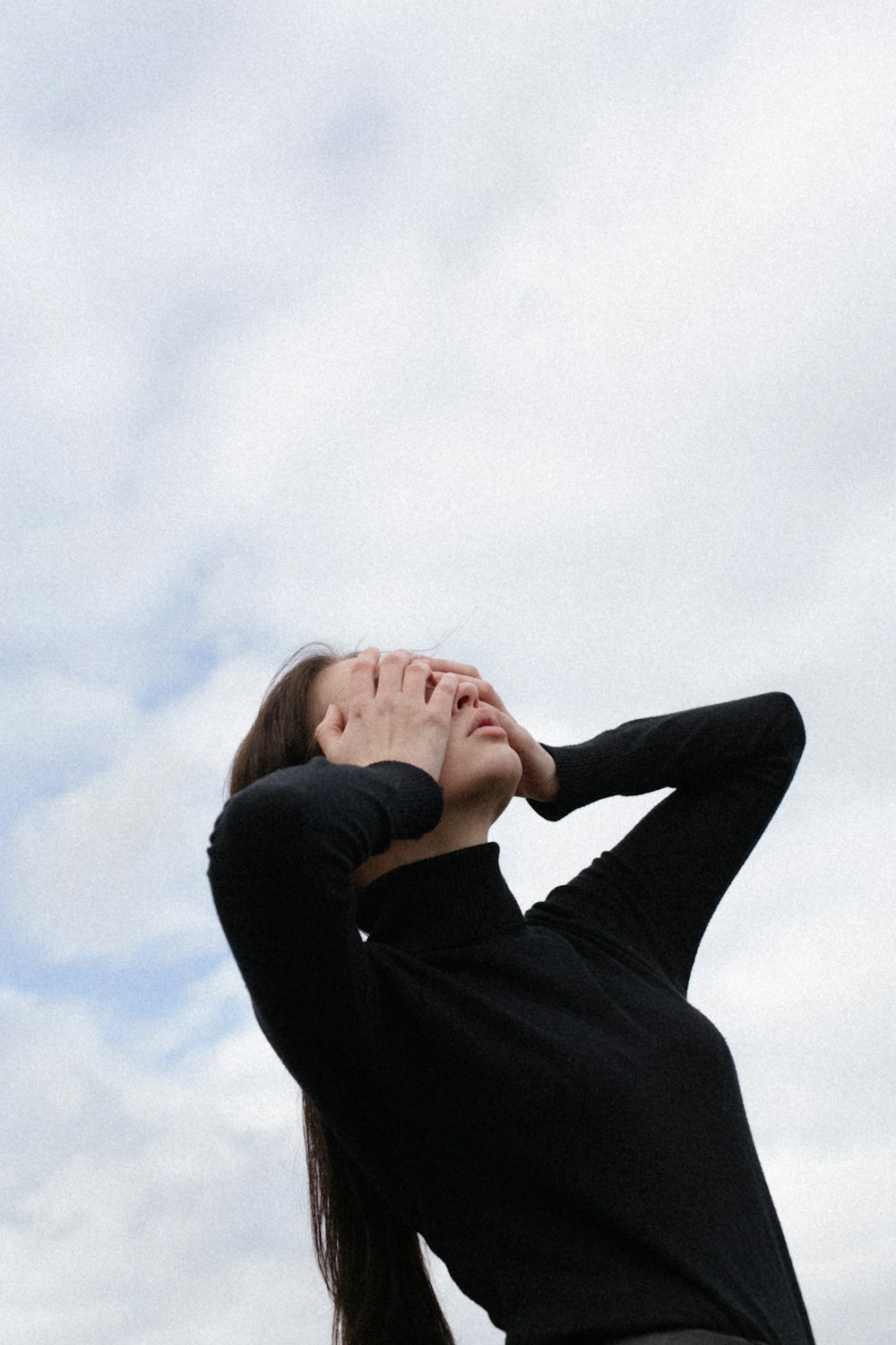 woman in black long sleeve shirt covering her face with her hands