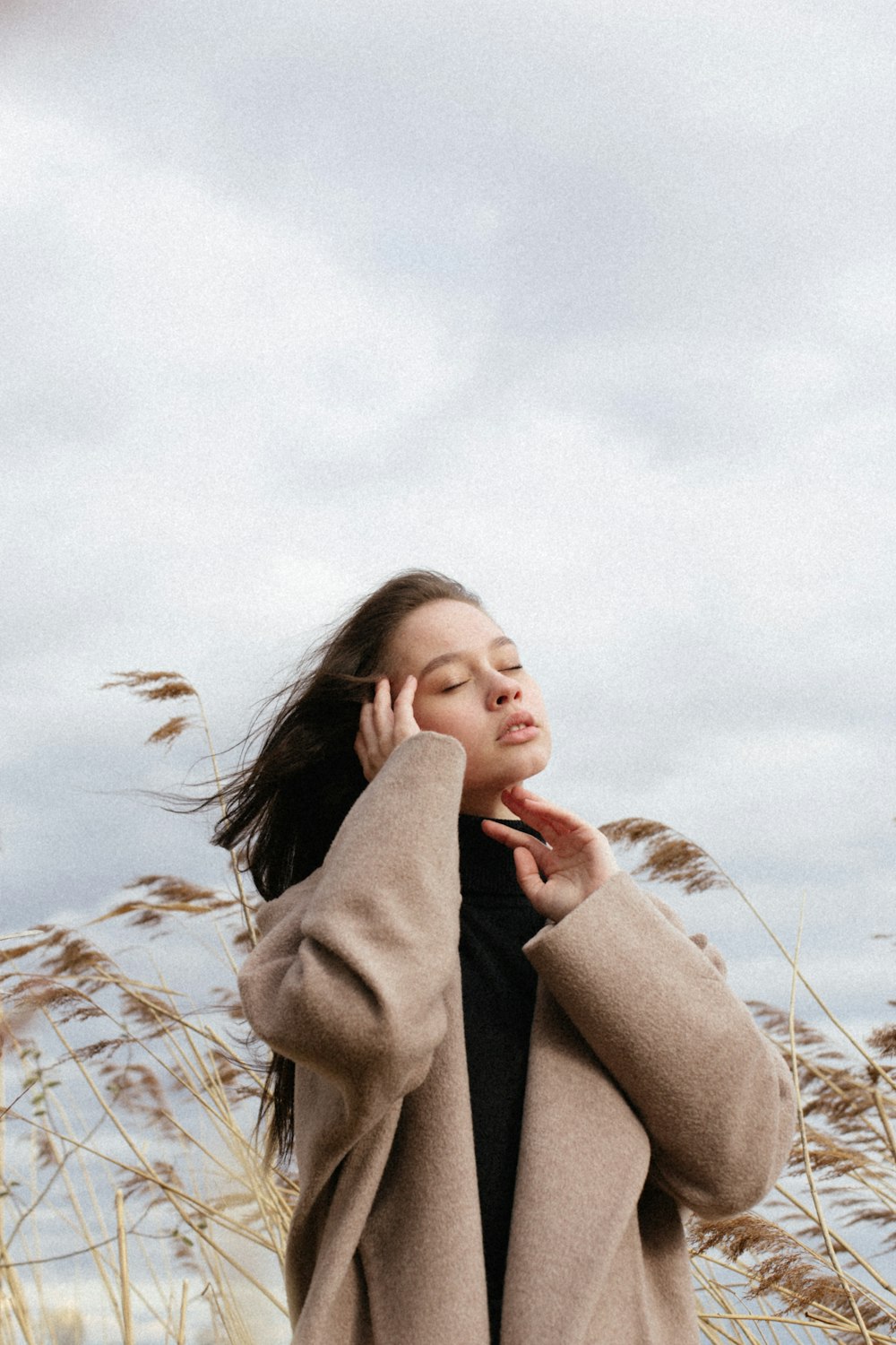 woman in brown coat standing on brown grass field during daytime