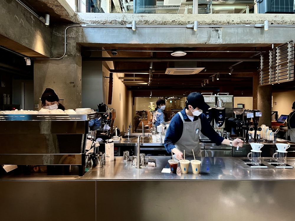 man in blue long sleeve shirt standing beside counter