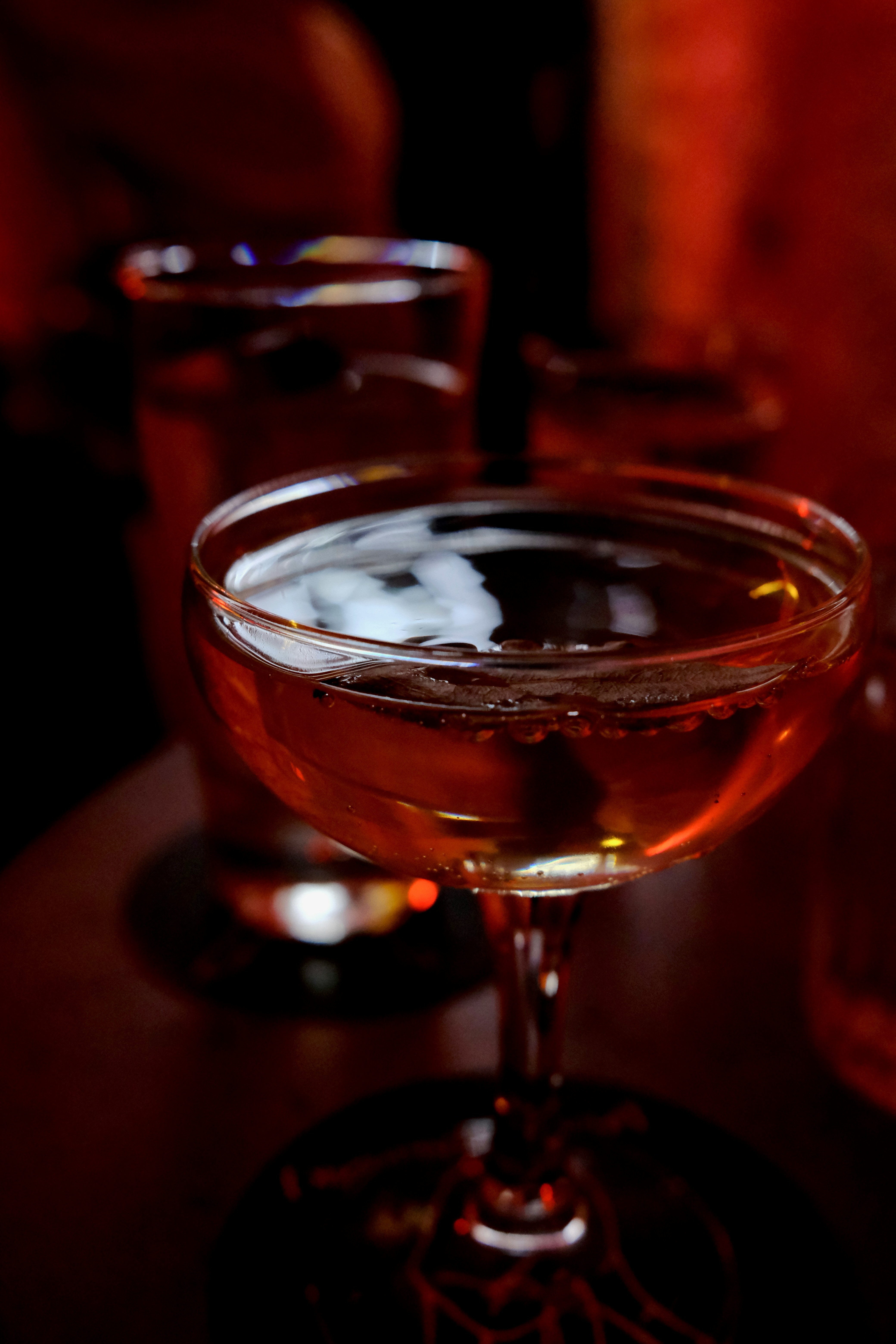 A beautifully crafted cocktail in a dark, moody bar setting.