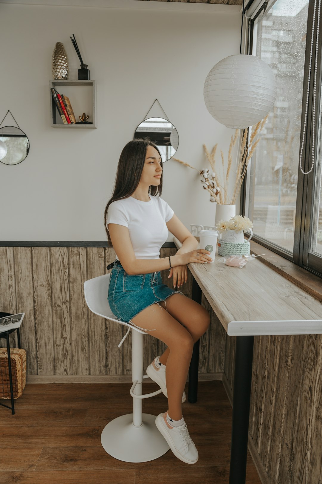 woman in white t-shirt and blue denim shorts sitting on chair