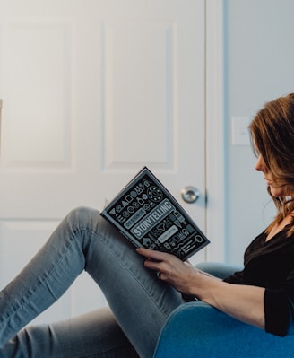 woman in black long sleeve shirt and blue denim jeans sitting on white table