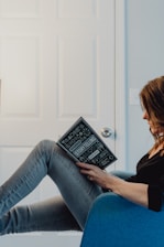 woman in black long sleeve shirt and blue denim jeans sitting on white table