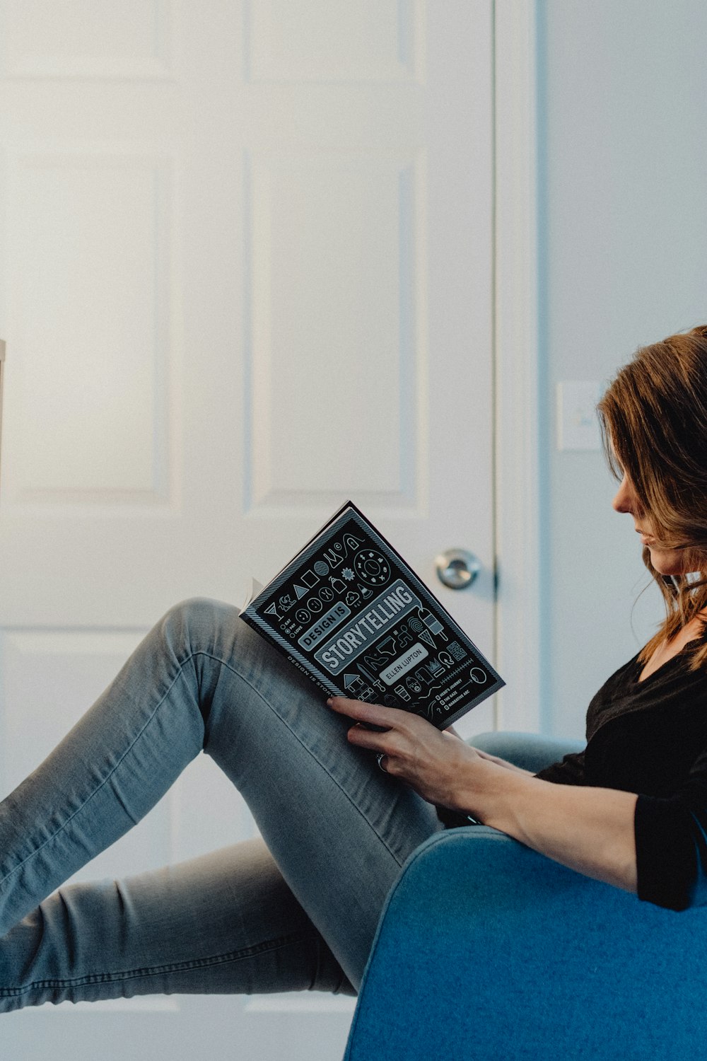 woman in black long sleeve shirt and blue denim jeans sitting on white table