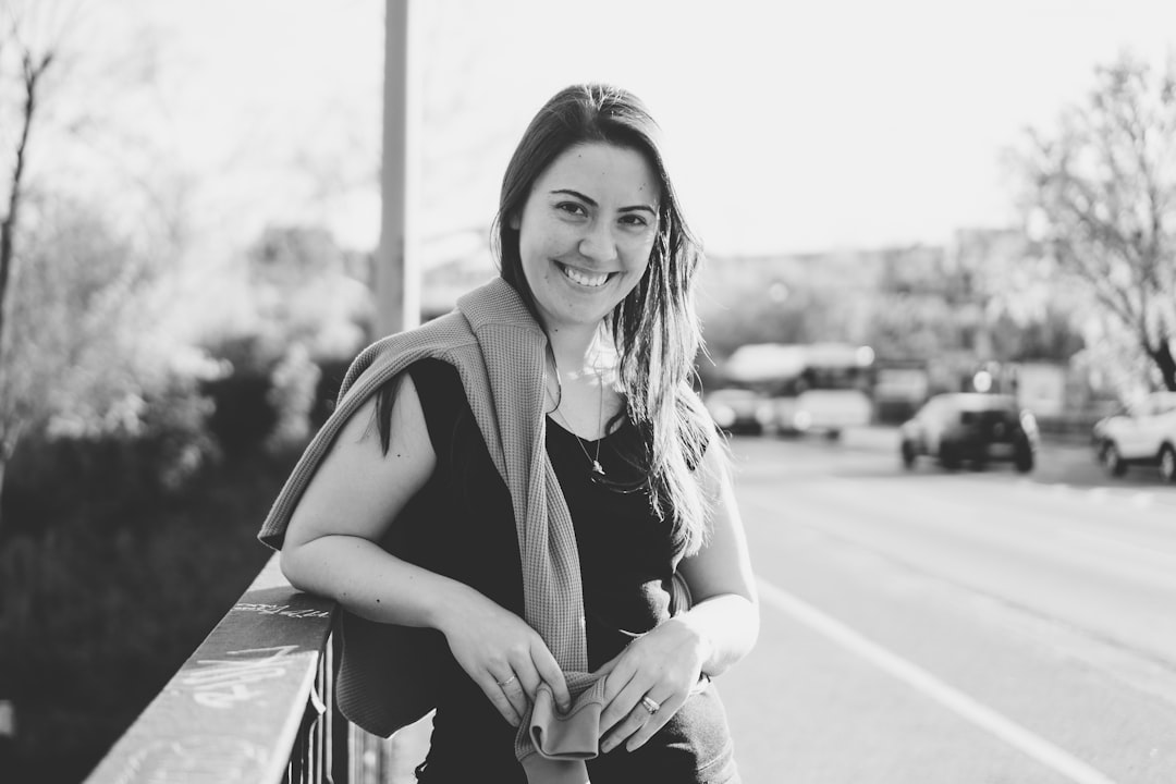 woman in black blazer and white pants sitting on the road