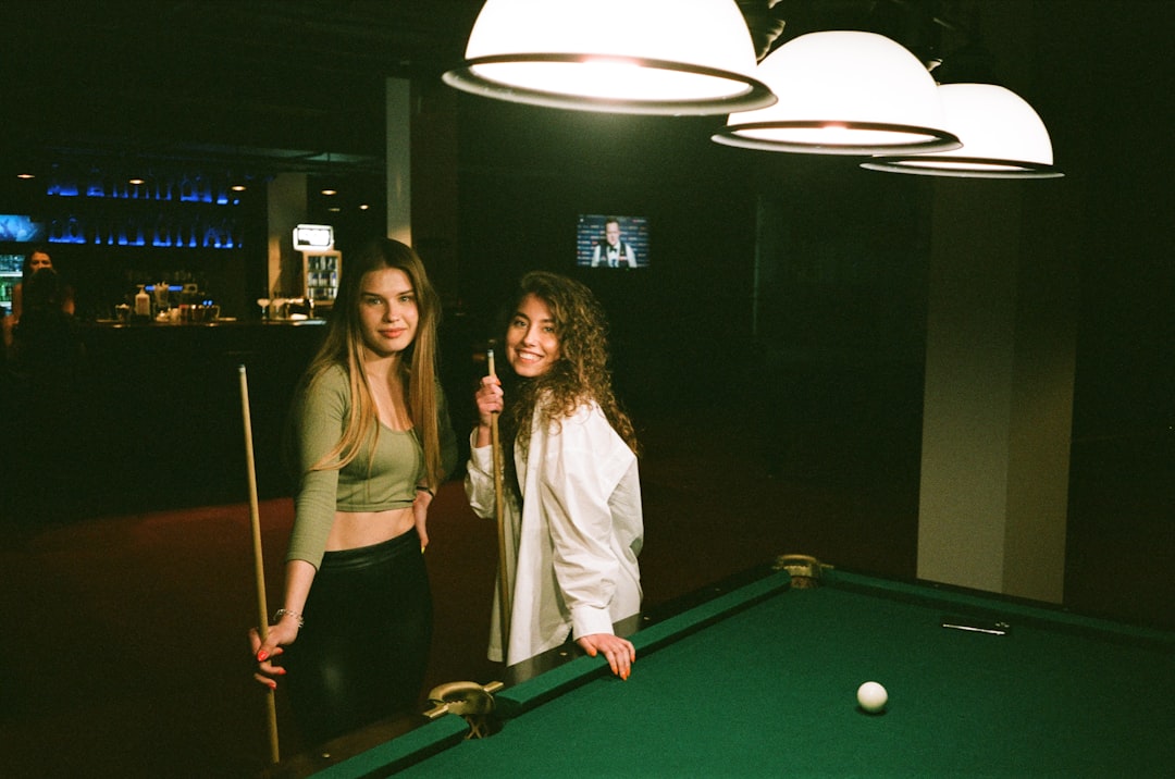 2 women standing beside billiard table