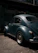 A happy middle-aged man standing proudly beside his restored vintage 1974 Volkswagen Beetle under soft natural light.