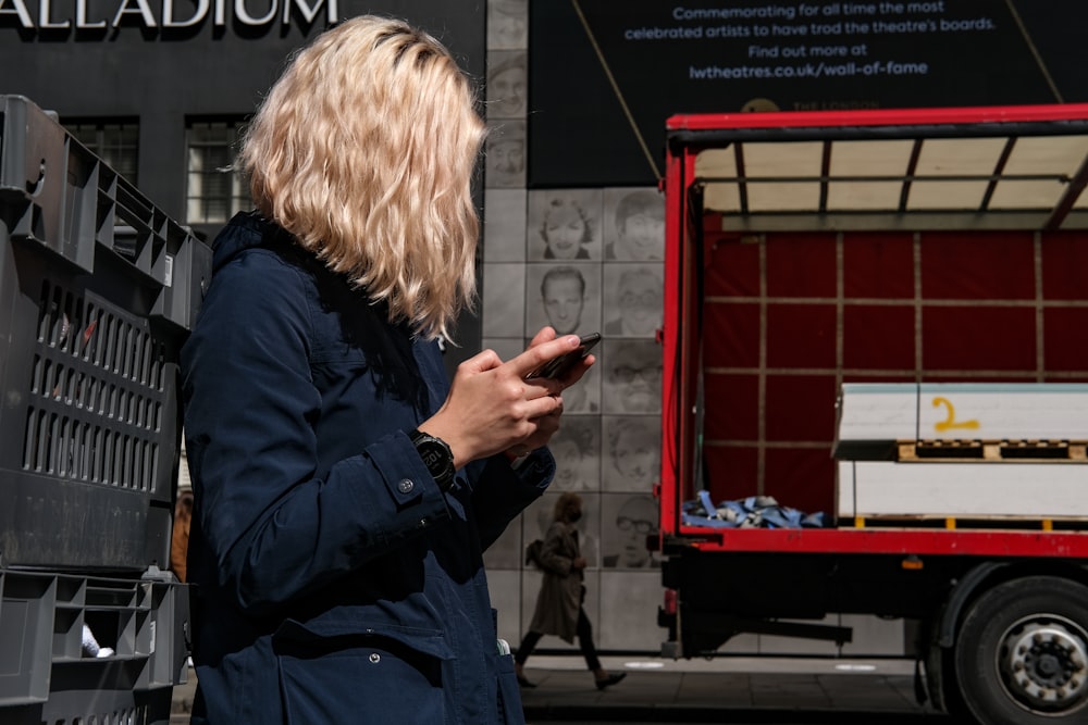 woman in blue jacket standing near red and white coca cola cooler