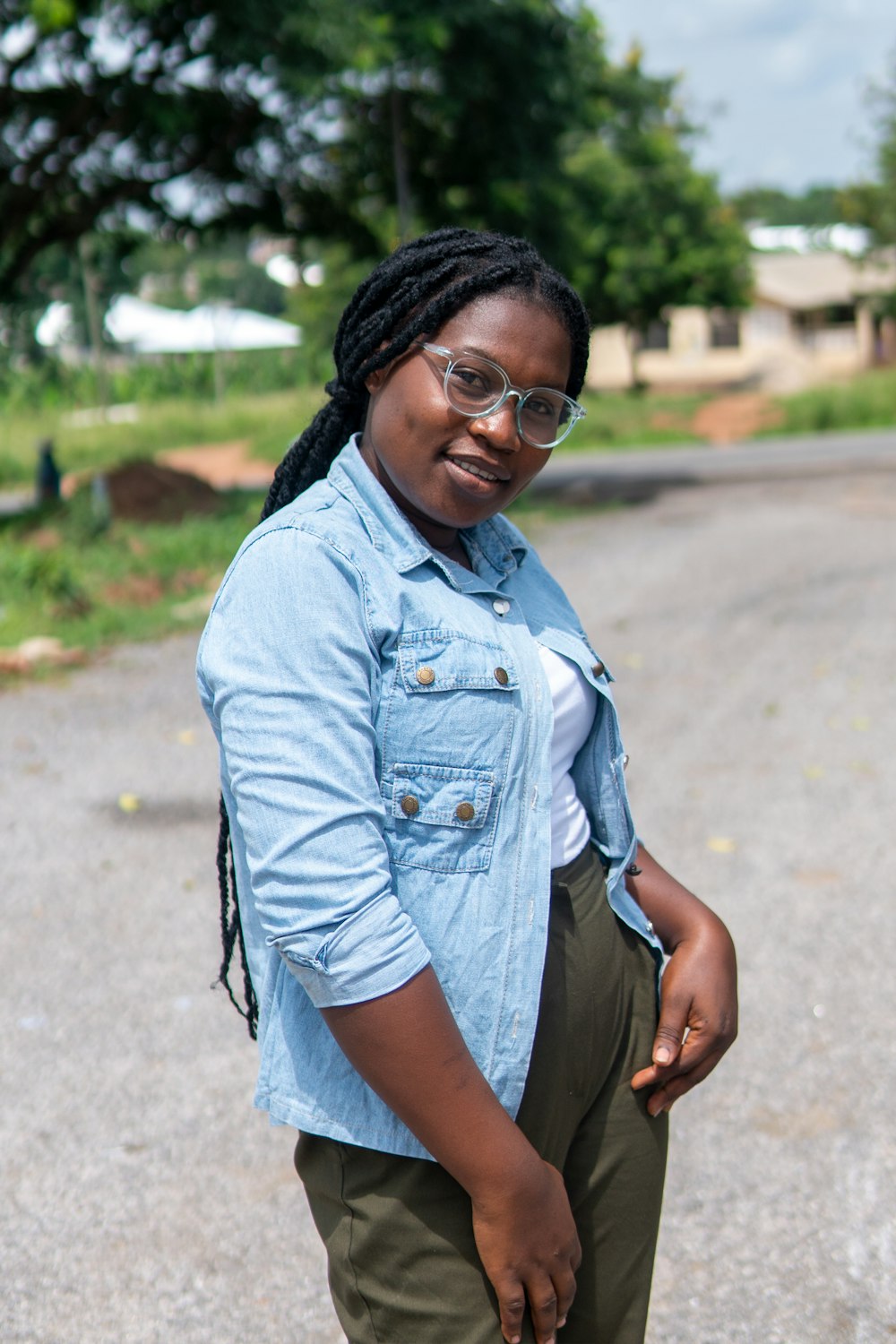 Femme en chemise boutonnée en jean bleu et short noir debout sur la route pendant la journée