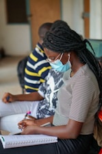 woman in white and black stripe shirt writing on white paper