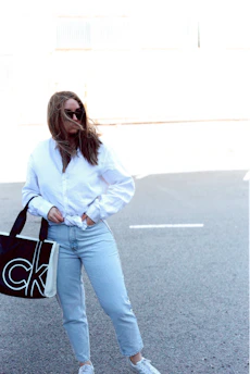 A happy customer carrying a full vėjas laundry bag through a sunny park.