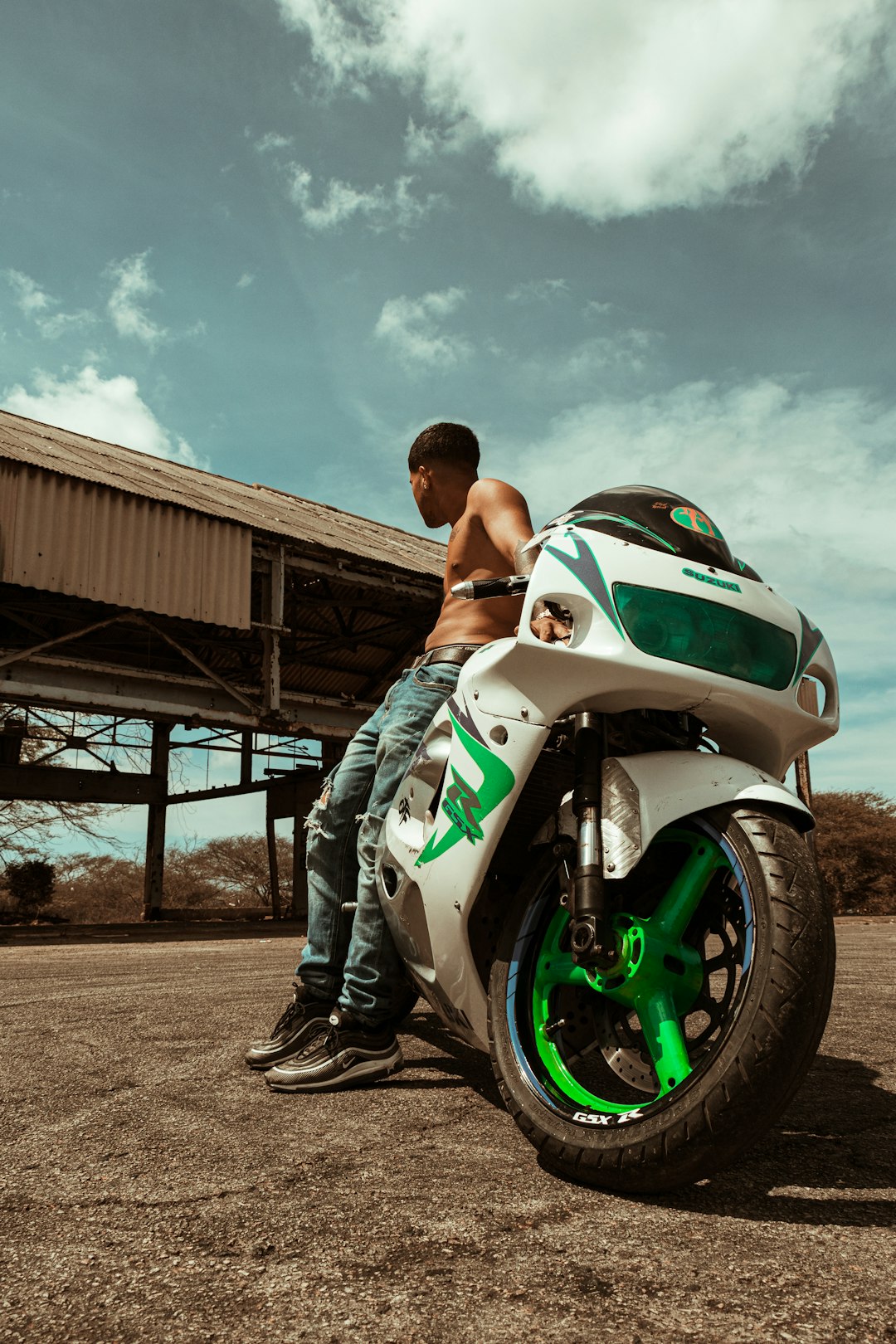 man in black tank top and black shorts sitting on green and white sports bike during