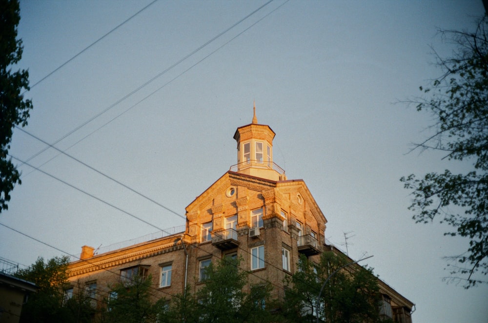 brown concrete building near green trees under white sky during daytime