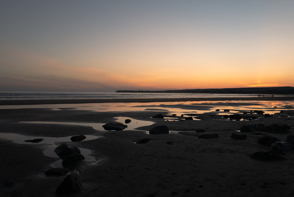 silhouette of rocks on beach during sunset