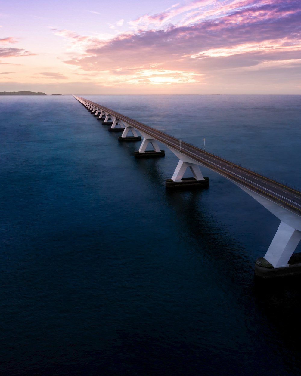 ponte de concreto branco sobre o mar azul sob o céu azul durante o dia