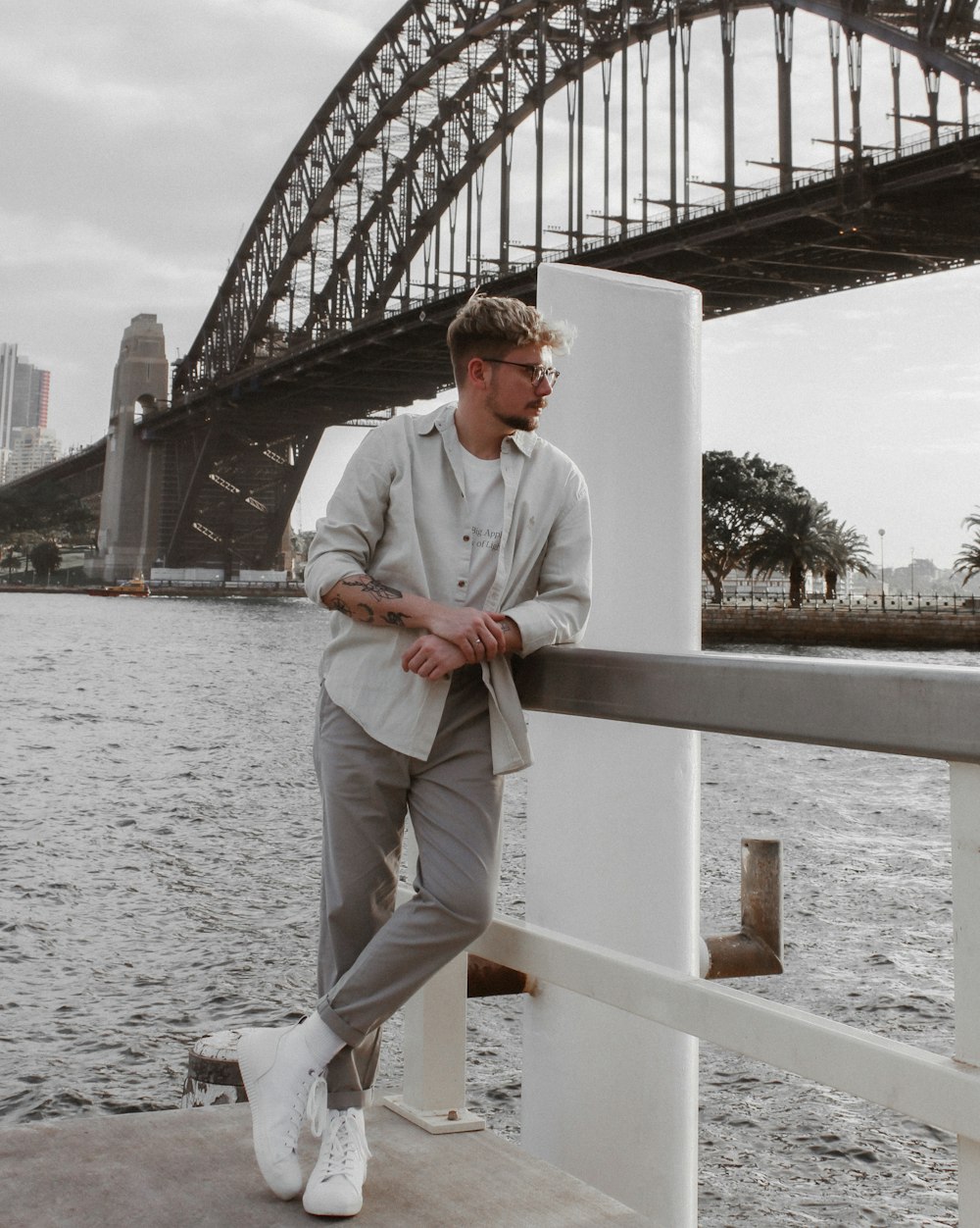 man in white dress shirt and white pants sitting on white wooden fence during daytime