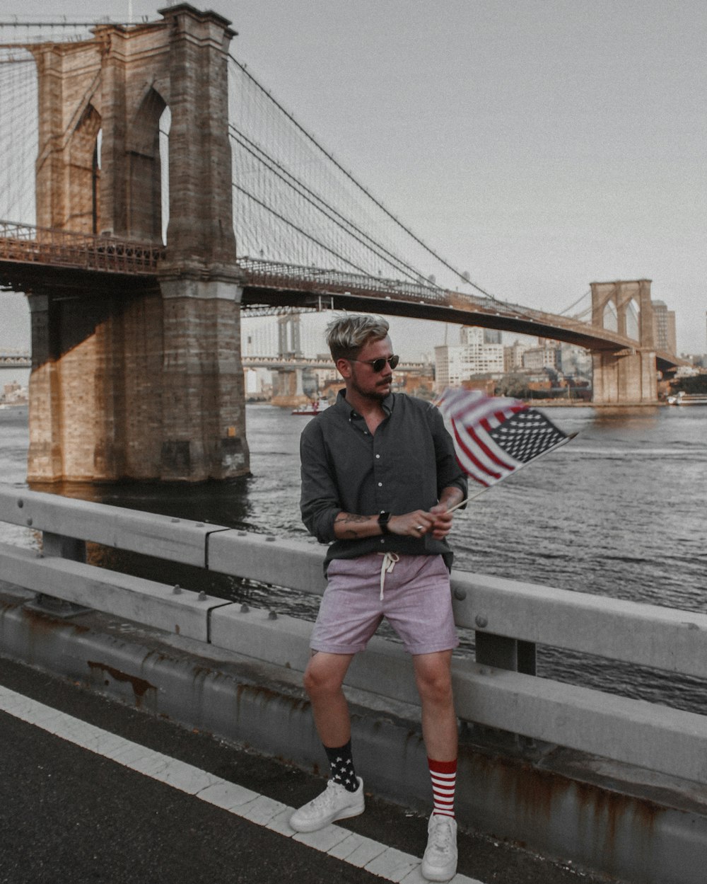 man in black jacket and pink shorts standing on gray concrete bridge during daytime