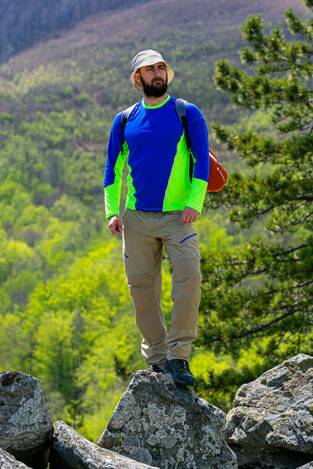 man in blue and red long sleeve shirt and brown pants standing on rock during daytime