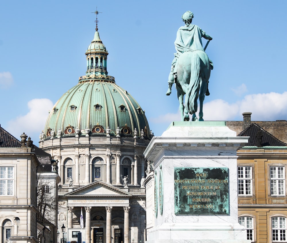 homem que monta estátua a cavalo perto do edifício de concreto branco durante o dia