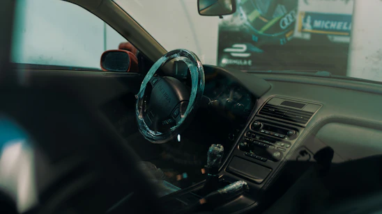 A close-up of a shiny car dashboard with foam and cleaning products around.