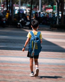 boy in blue and yellow t-shirt walking on sidewalk during daytime