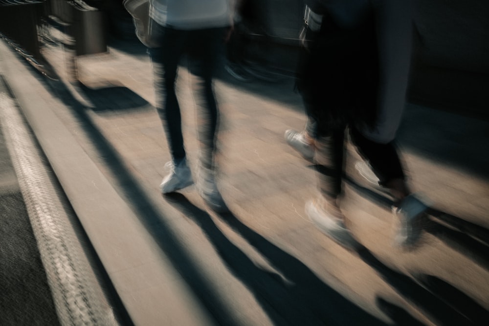 person in white shirt and blue denim jeans walking on sidewalk