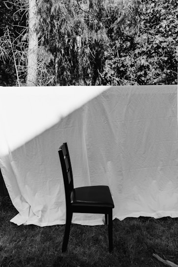 A striking black and white photo of a metal band t-shirt draped over a rustic wooden chair.