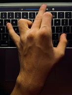 Close-up of hands adjusting settings on a laptop with senior-friendly interface.