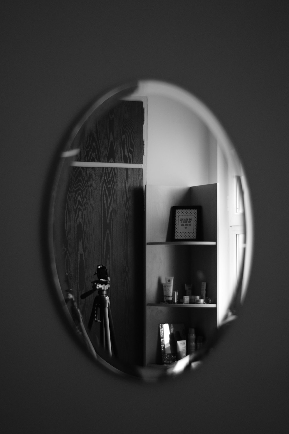 Foto en escala de grises de un hombre de pie frente al espejo
