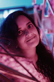 Soft pink themed photo of Nany Palacio Love smiling warmly.