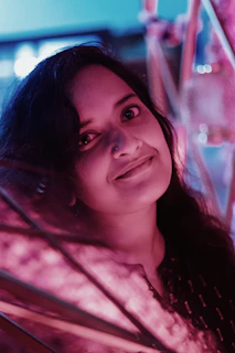 A warm photo of Daniela smiling gently, surrounded by soft pink and purple hues.