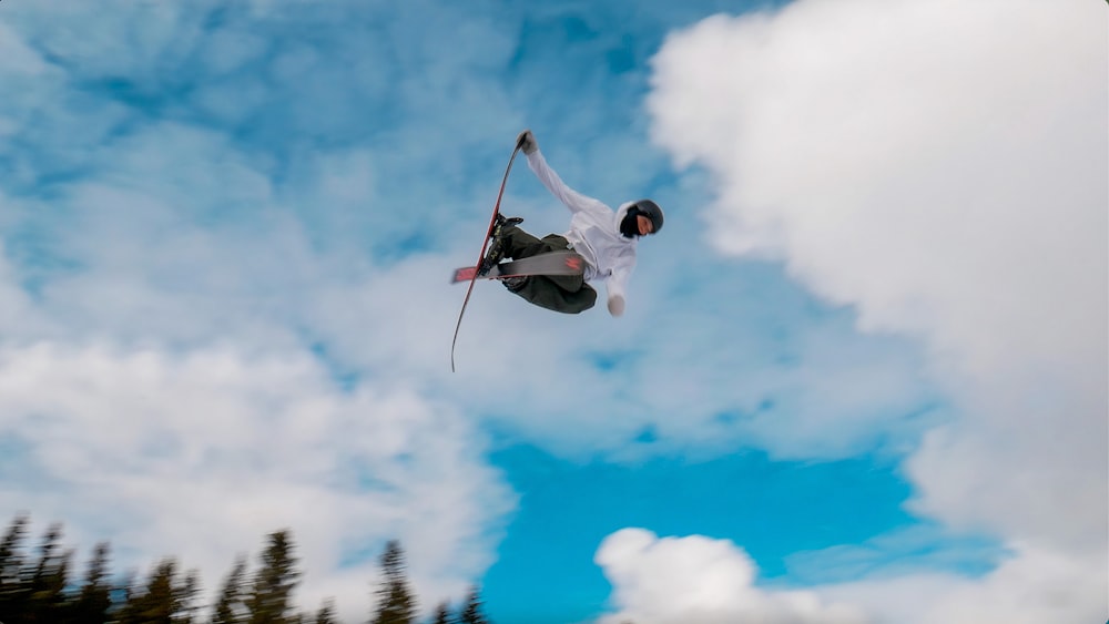 man in white shirt and blue denim jeans jumping on mid air under blue and white