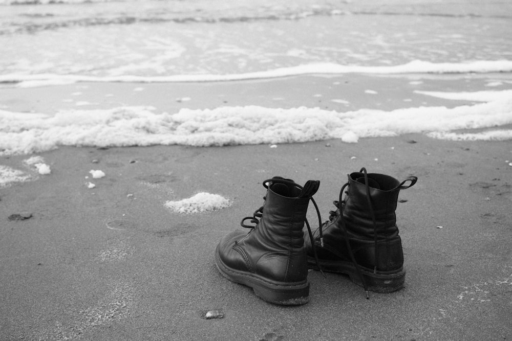 botas de couro preto na costa da praia