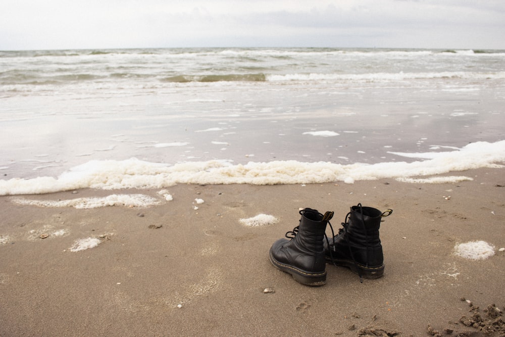 botas de couro preto na praia de areia marrom