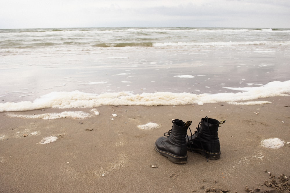 schwarze Lederstiefel am braunen Sandstrand