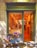 A quaint bakery storefront with a sign reading 'Martina Sweet Cakes' features a charming blue bicycle adorned with baskets of vibrant flowers parked outside. Inside, the warm glow highlights the decorative interior and pastries on display.
