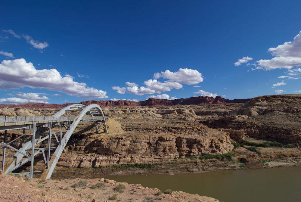 white metal bridge on brown rocky mountain under blue sky during daytime