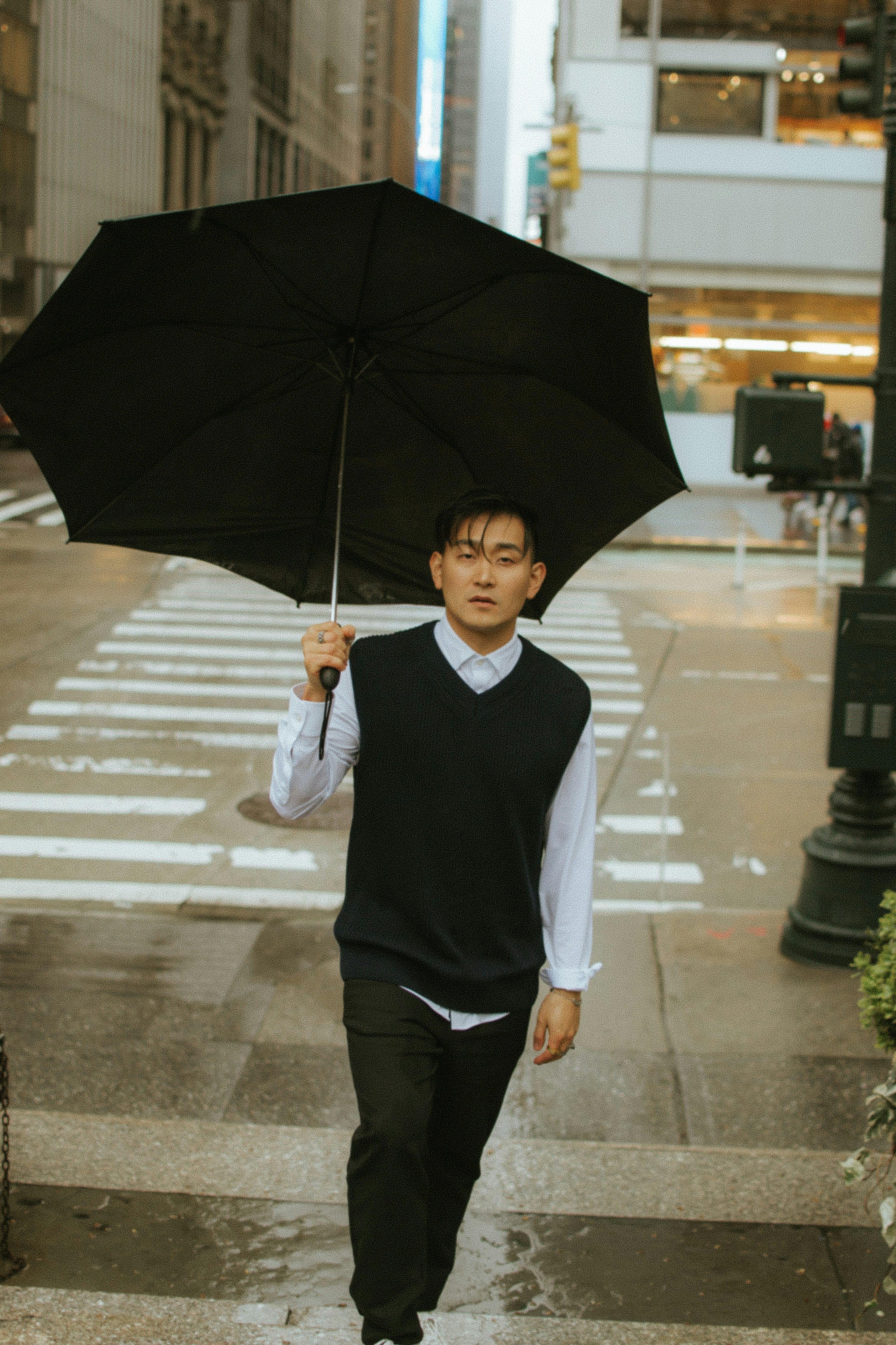 man in black vest holding umbrella