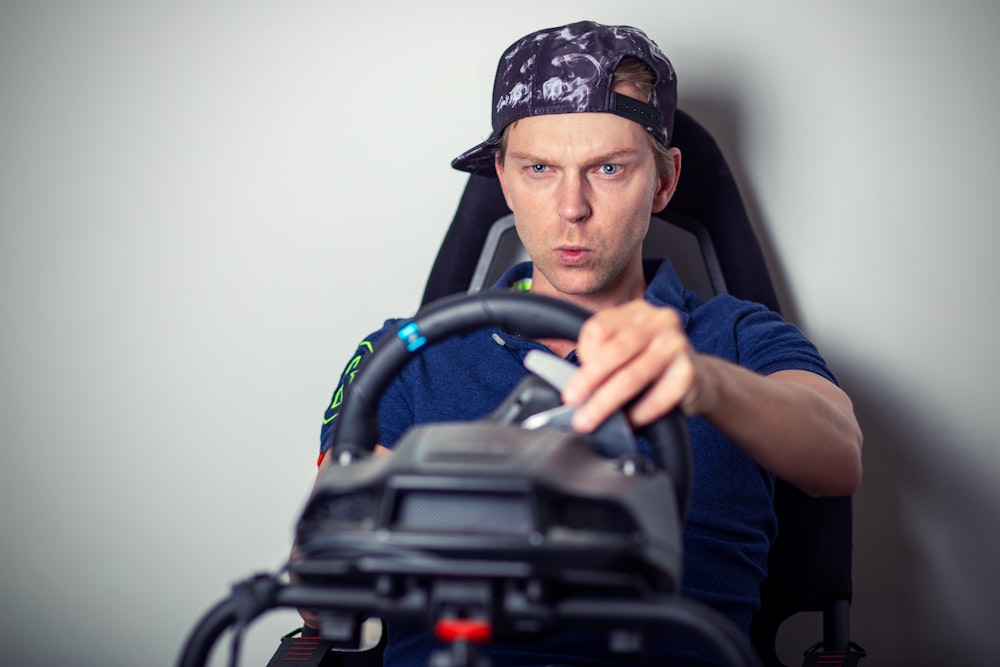 man in blue crew neck t-shirt wearing blue and white cap sitting on black office