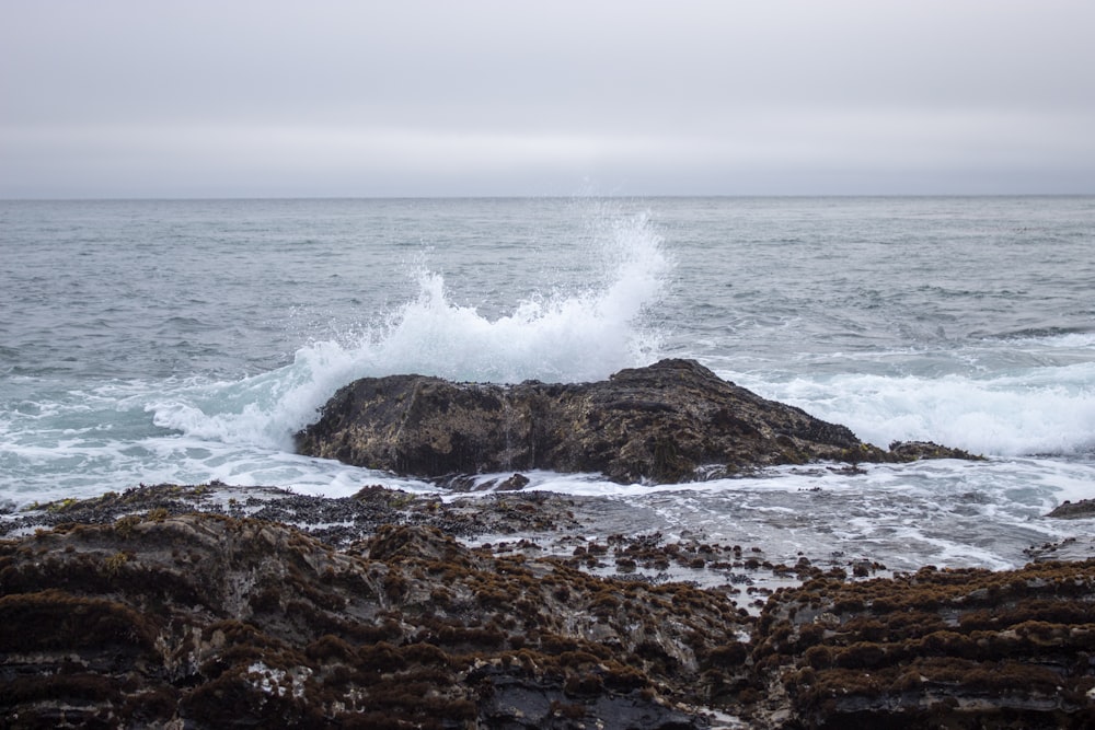 Olas del océano rompiendo contra la formación de rocas marrones durante el día
