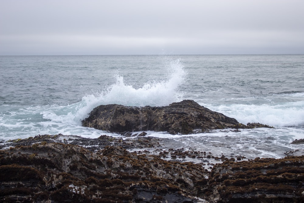 ocean waves crashing on brown rock formation during daytime